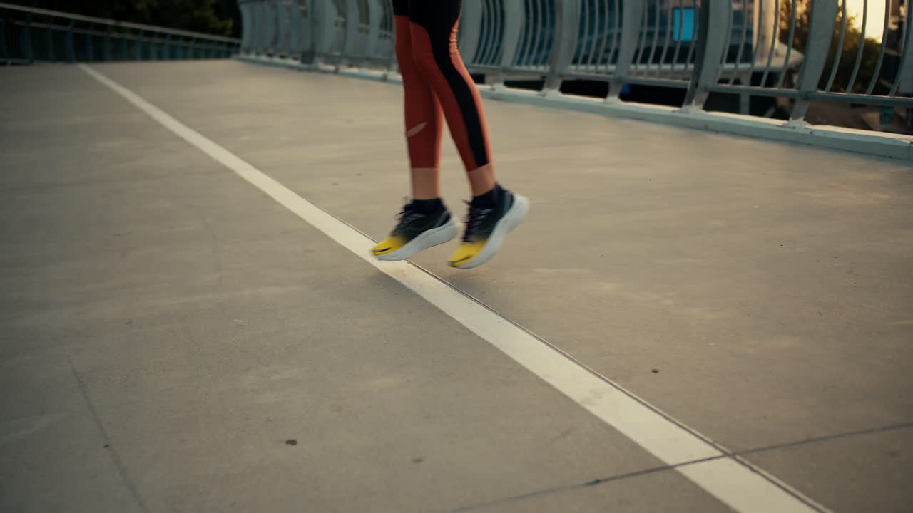 Close-up shot of a girl in a sports uniform and sports sneakers running in place and warming up before a morning run on the road