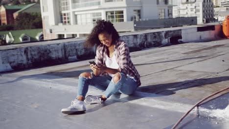 Fashionable-young-woman-on-urban-rooftop-using-smartphone