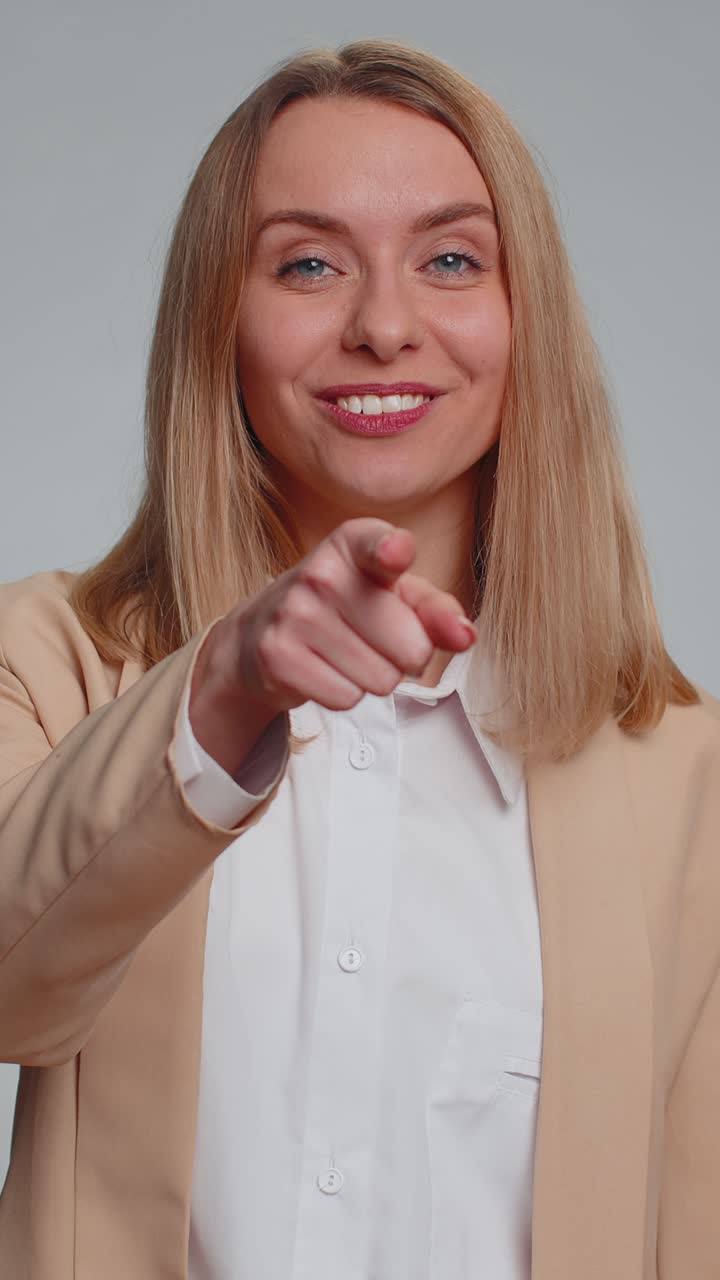 Eine Frau zeigt auf die Kamera und schaut mit einem spielerischen, glücklichen Gesichtsausdruck, macht eine Wahl, zeigt eine Richtung