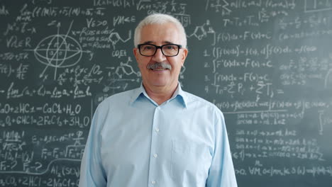 smiling professor in front of a chalkboard full of equations
