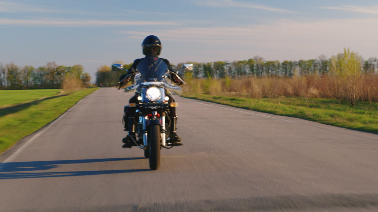 motociclista montando a lo largo de una estrecha carretera asfaltada de vídeo de alta definición