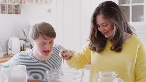 Young-Downs-Syndrome-Couple-Measuring-Ingredients-To-Bake-Cake-In-Kitchen-At-Home