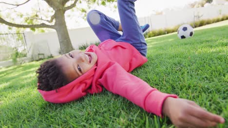 portrait of happy african american boy laying on grass in garden