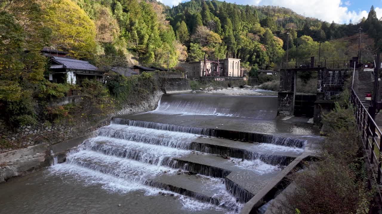 Cascading Araragi River flows through the picturesque landscape of Tsumago juku, showcasing traditional architecture and a functional weir