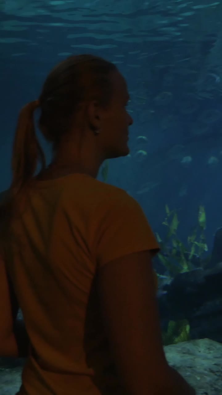 Jovem Mulher Observando um Tubarão Nadar em um Grande Aquário