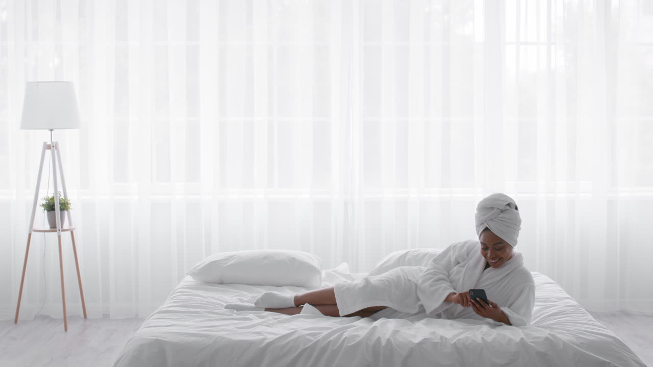 mujer relajándose en la cama con un teléfono inteligente