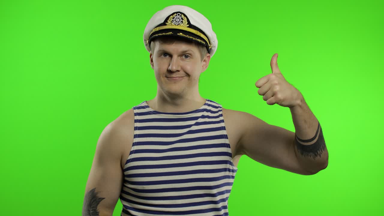 joven marinero pulgares hacia arriba, mirando a la cámara. marinero tipo en chaleco de marinero