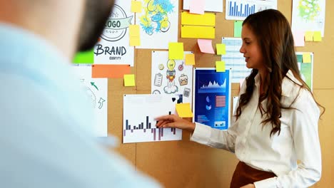 Business-colleagues-discussing-over-bulletin-board