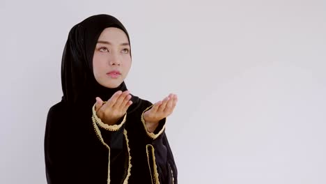 muslim woman asia wear black clothes and cover hijab raising their hands to ask for blessings from god in the living room at home. religious belief and smiling happily