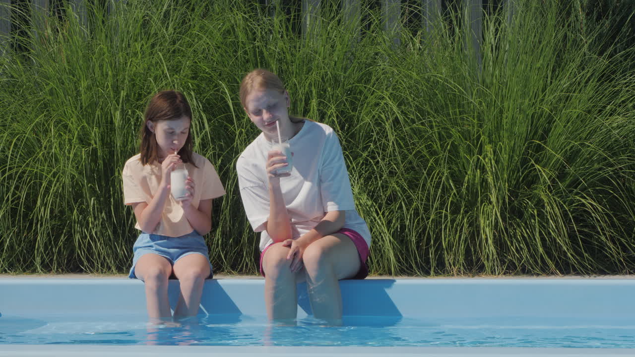 두 소녀가 수영장 에서 밀크 이크를 즐기고 있다