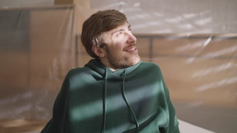 man in a green hoodie enjoying sunlight indoors