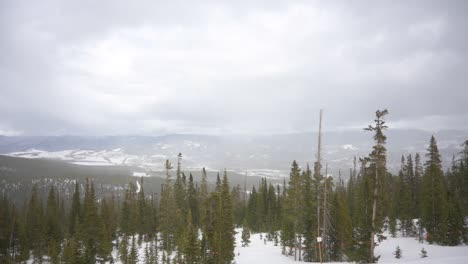 Tormenta-De-Nieve-Que-Sopla-Sobre-Montañas-Distantes-Con-Pinos-En-Primer-Plano,-Estática