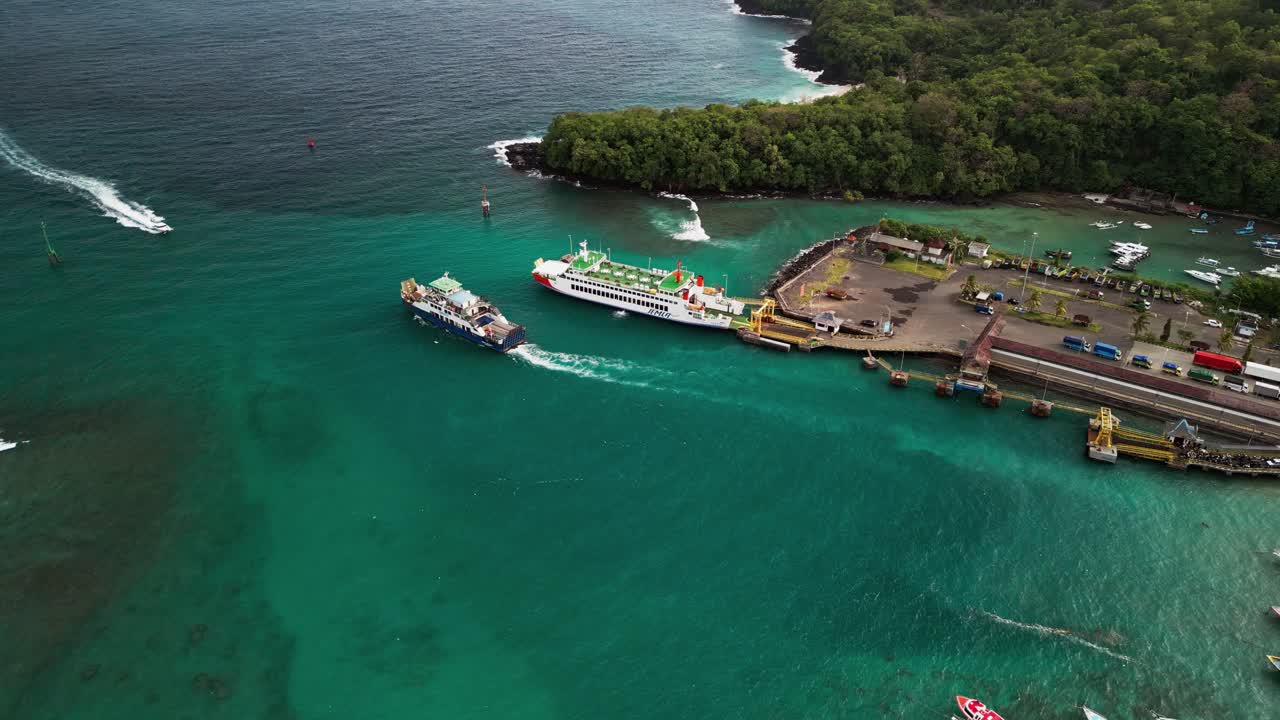 Drone footage of Padang Bai Harbor, Bali, where a ship leaves the pier surrounded by bright water, scenic coastline, and peaceful maritime atmosphere under soft sunlight