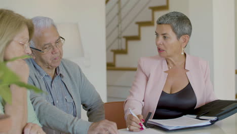 female realtor sitting at table, talking with clients and discussing details of the contract