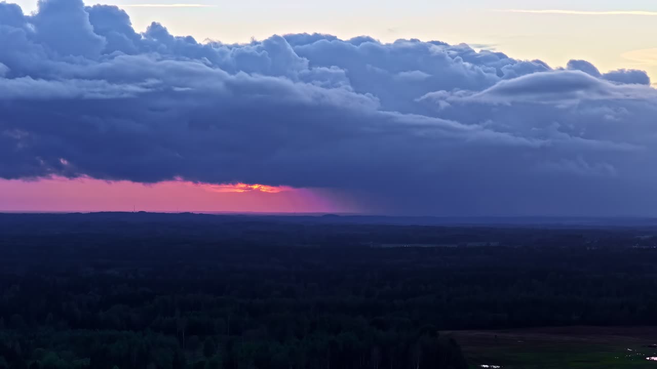 Storm clouds approaching during dramatic sunset over forest horizon in Latvia