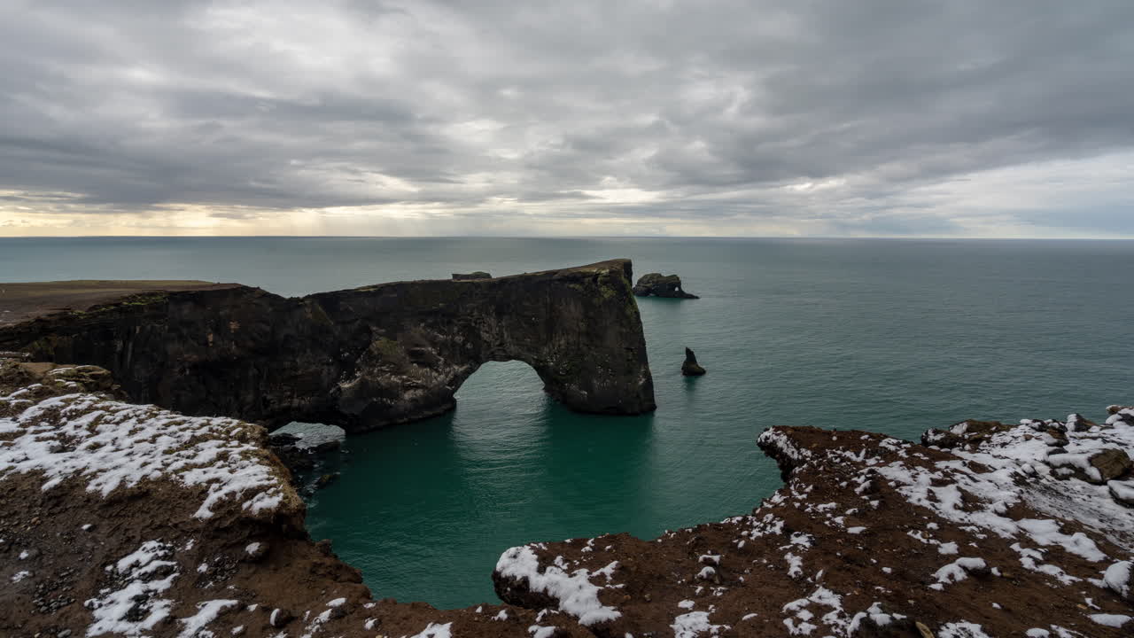 Timelapse of Dyrholaey Natural Arch, Landmark of Iceland, Moving Clouds Above Ocean and Coastline