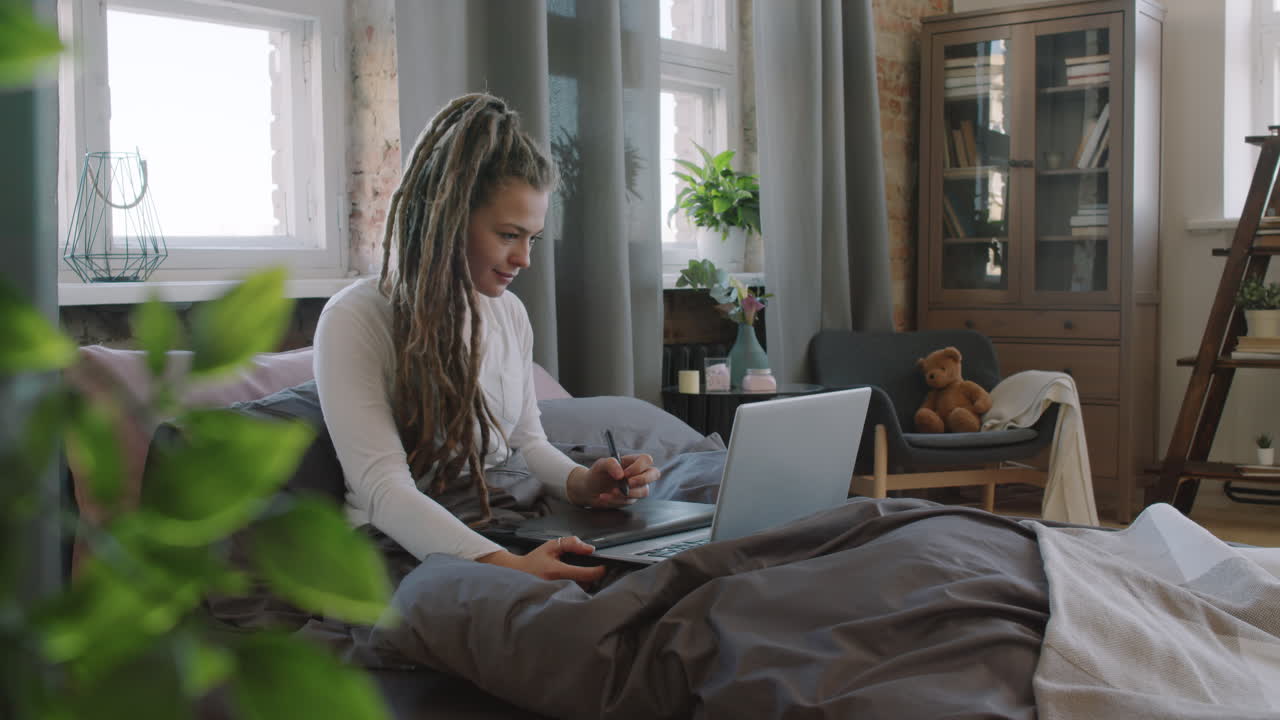 Woman Working On Drawing Tablet In Bed