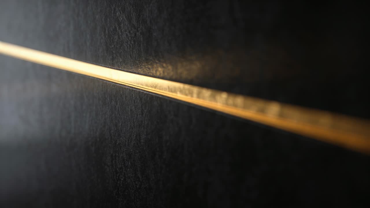 Striscia dorata che riflette la luce cangiante in primo piano, foschia che si sposta, rivelando la texture per il design.