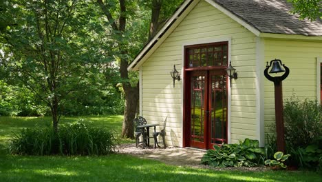 static-shot-of-a-white-building-with-a-red-door-with-a-small-set-of-table-and-chairs-in-front-of-it