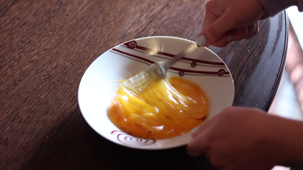 mezclar a mano huevos revueltos en placa de cerámica - ángulo alto, cerrar