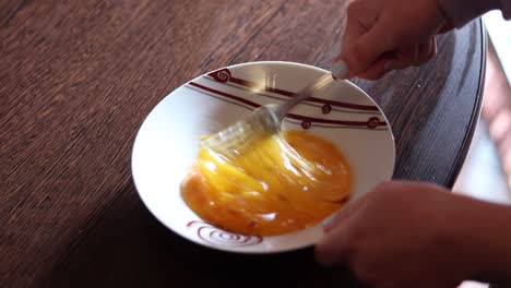 hand mixing scramble egg in ceramic plate - high angle, close up