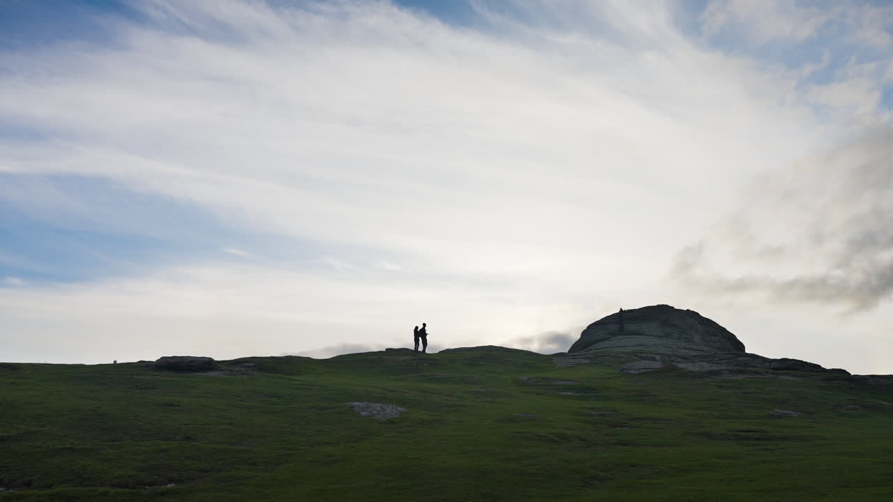 People standing on a hilltop at sunset