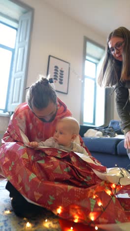 family unwrapping christmas gift for baby