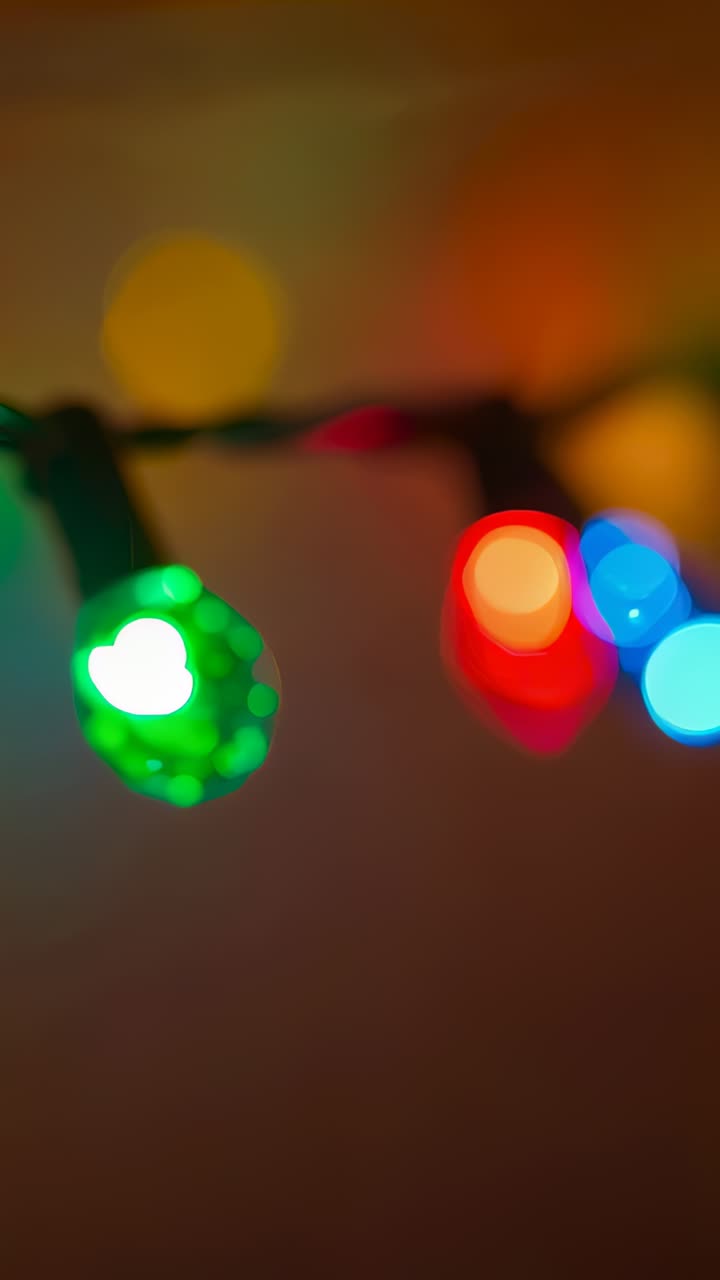 Vertical video: Shifting camera moving faceted string lights across dim wall, changing bokeh