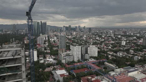 sobrevuelo aéreo: grúa de torre de construcción de edificios en la nublada ciudad de méxico