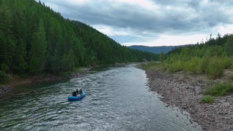 tourists rafting on the flathead river through pine forest in montana, usa