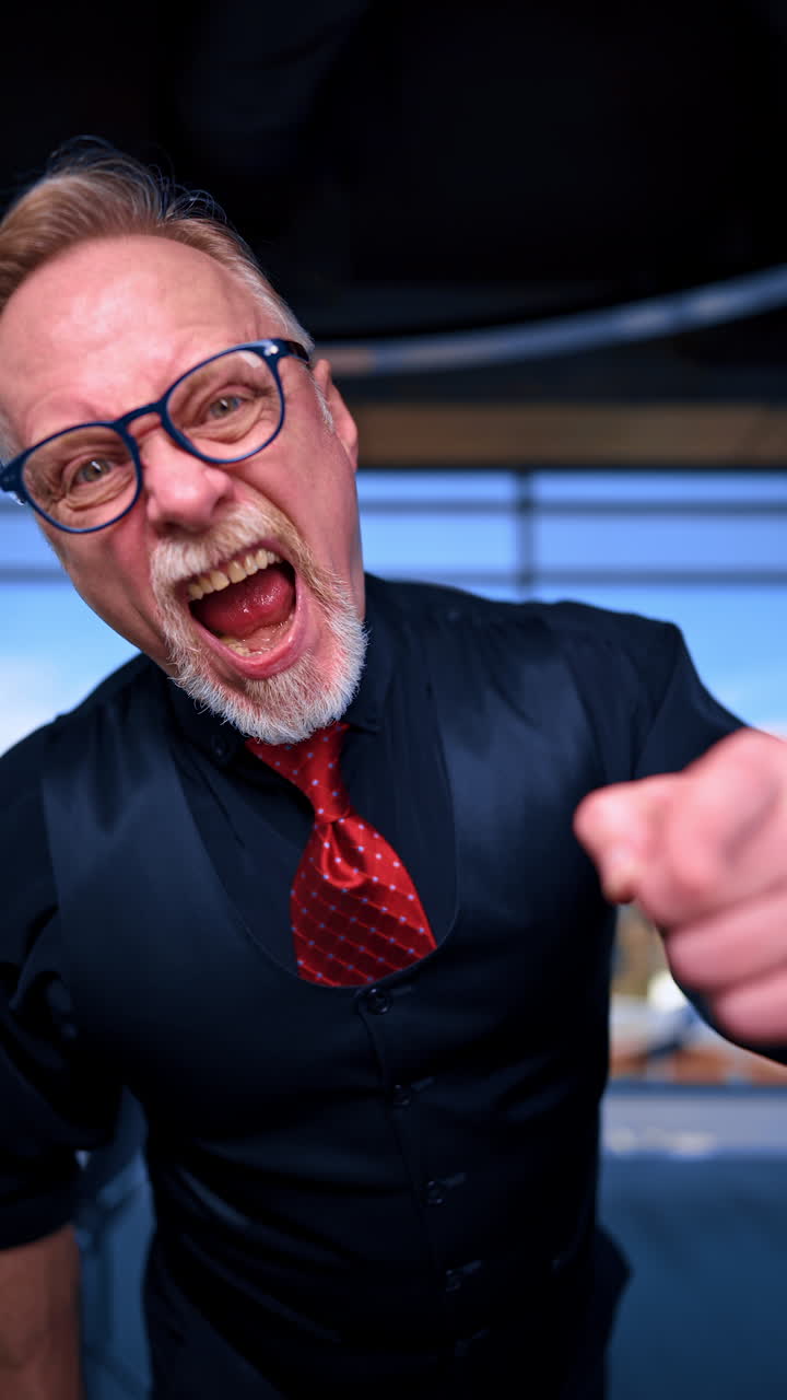Caucasian man in glasses, shirt, vest and tie telling off somebody in front of camera. Close up portrait of a boss firing the employee with scandal. Vertical video.