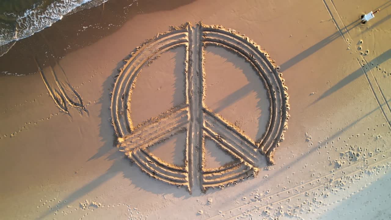 Gliding drone launching, capturing peace symbol carved in sand at beach to record art and tracks