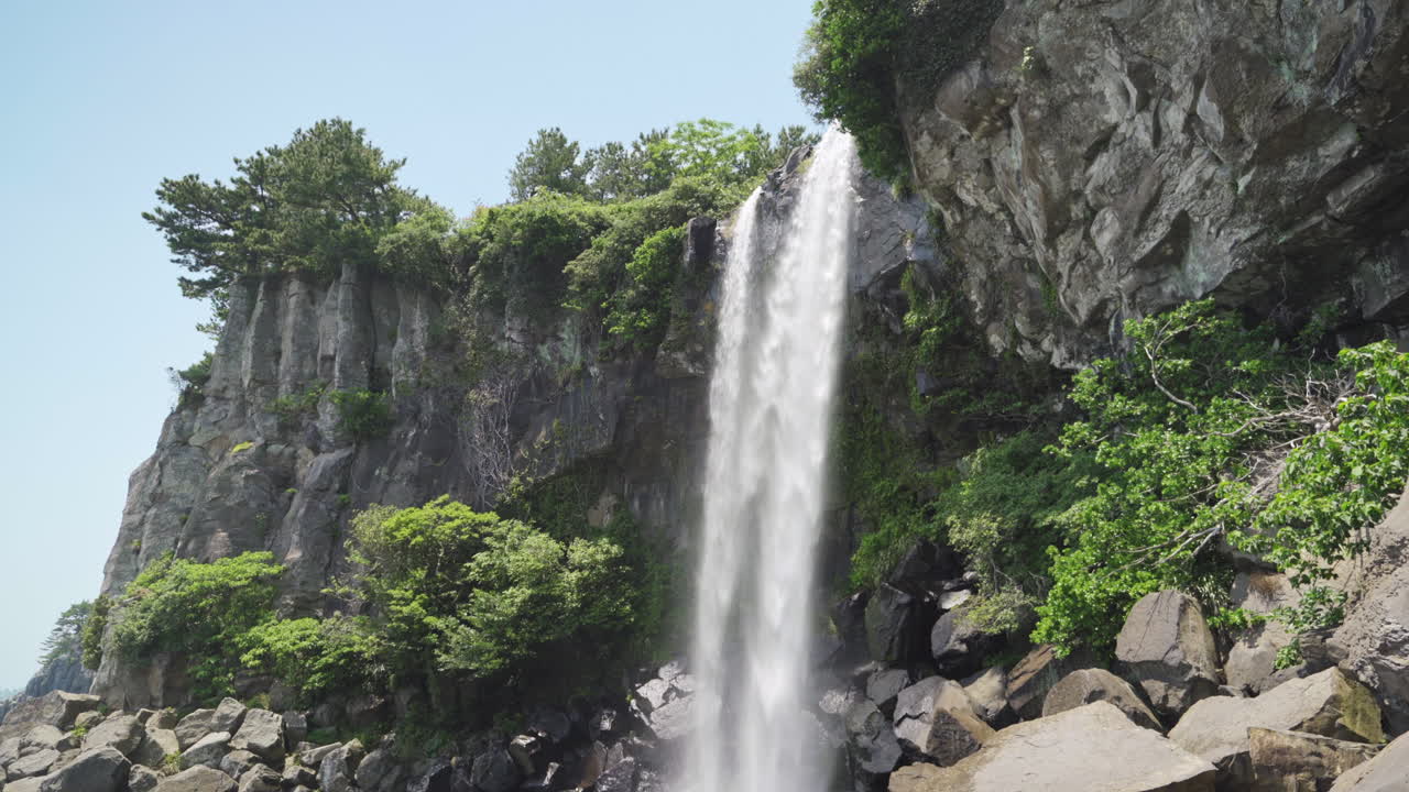 Jeongbang Falls on Jeju Island, South Korea, during the Spring, wide tilt down in 4K.
