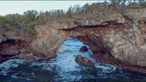 aerial flight approaching famous natural arch of la hondonada and splashing waves of caribbean sea