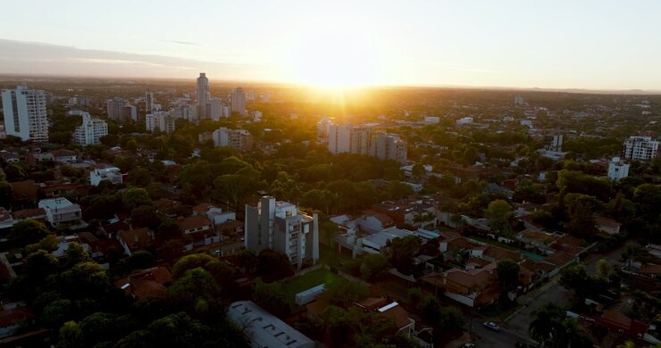 Veduta aerea di Asunción al tramonto con bagliore solare sullo skyline e sui quartieri residenziali. Cattura la luce calda, lo sviluppo urbano e l'atmosfera nella capitale del Paraguay