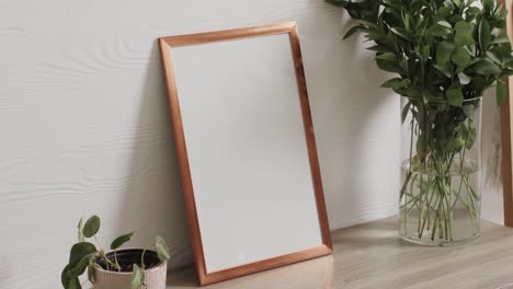 wooden frame with copy space on white background with plants on desk against white wall