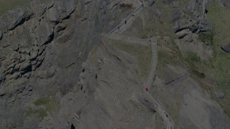 tourists climb the stone steps of gaztelugatxe islet in northern spain