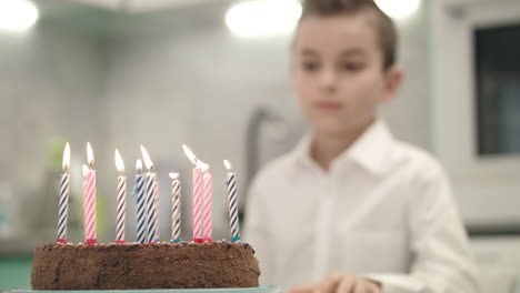 boy looking on birthday cake with candle flames. happy birthday concept