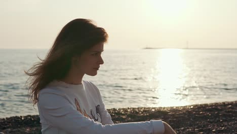 mujer sentada en la playa al atardecer