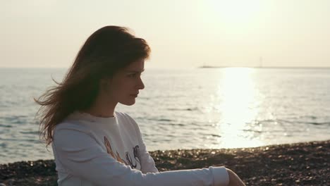 woman sitting on beach at sunset