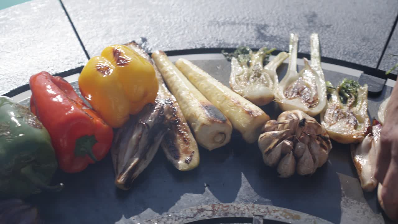 establishing shot of a various selection of vegetables and meats cooked on a bbq