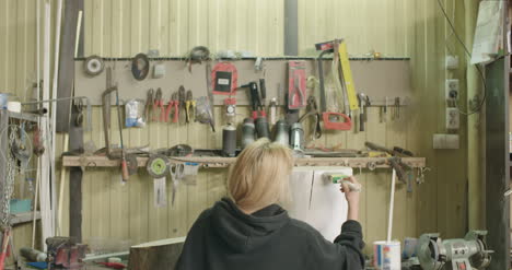 woman painting tree stump in workshop