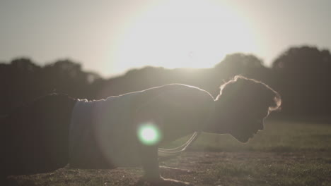 un joven atractivo haciendo flexiones en el parque durante la hora dorada en cámara lenta, sin clasificar.