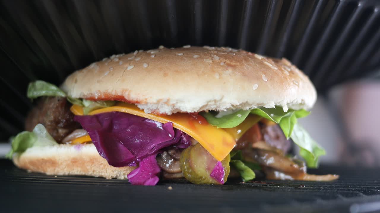 primer plano de una deliciosa hamburguesa a la parrilla con queso, lechuga, tomate, cebolla y pepinillos