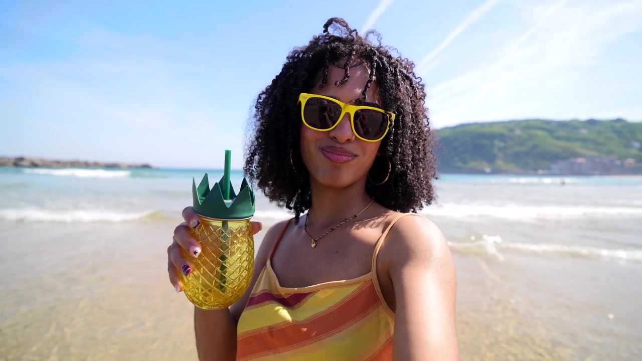 Jovem mulher feliz com bebida de abacaxi em uma praia ensolarada
