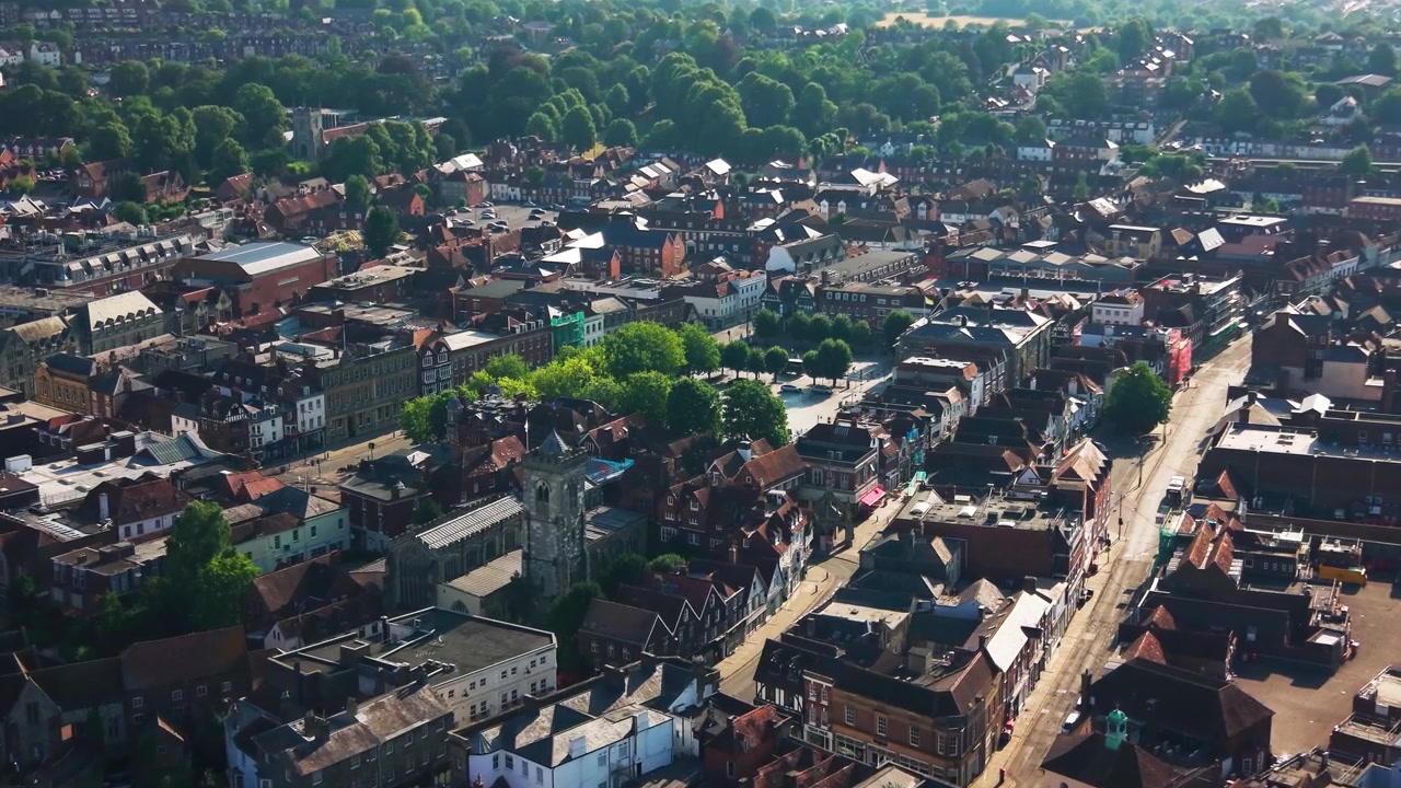 Wide drone view across Salisbury city centre showing St Thomas Church Market Place historic rooftops streets and green neighbourhoods in Wiltshire on a sunny summer day