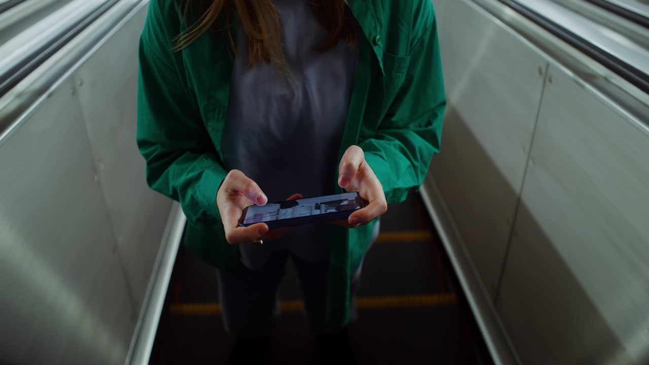 Woman using mobile phone on escalator