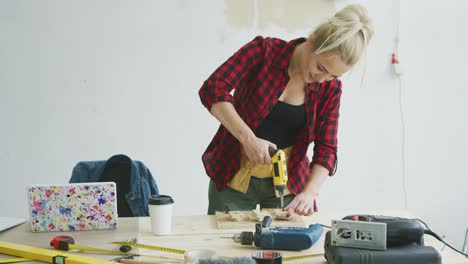 Female-drilling-wooden-plank-on-workbench-