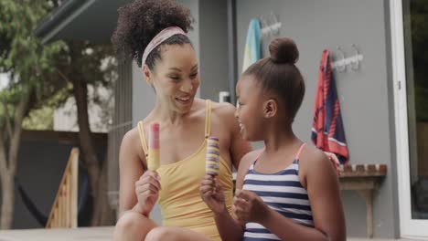 retrato de una madre y una hija afroamericanas comiendo helado junto a la piscina, cámara lenta