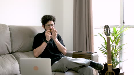 Caucasian-adult-man-plays-harmonica-following-instructions-on-notebook